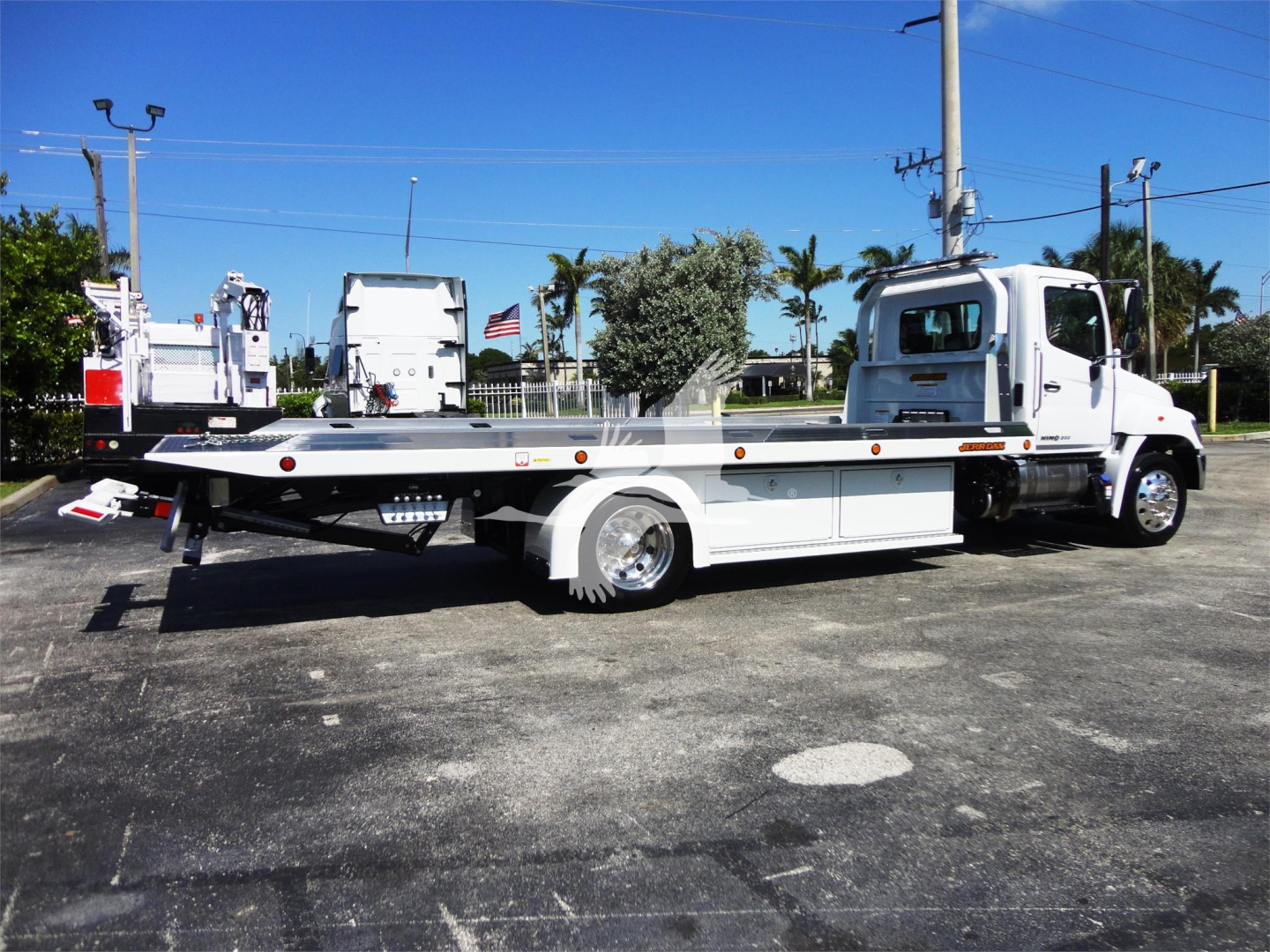 Hino 268A rollback tow truck side view with flatbed and cab, white color, stock number J51795.