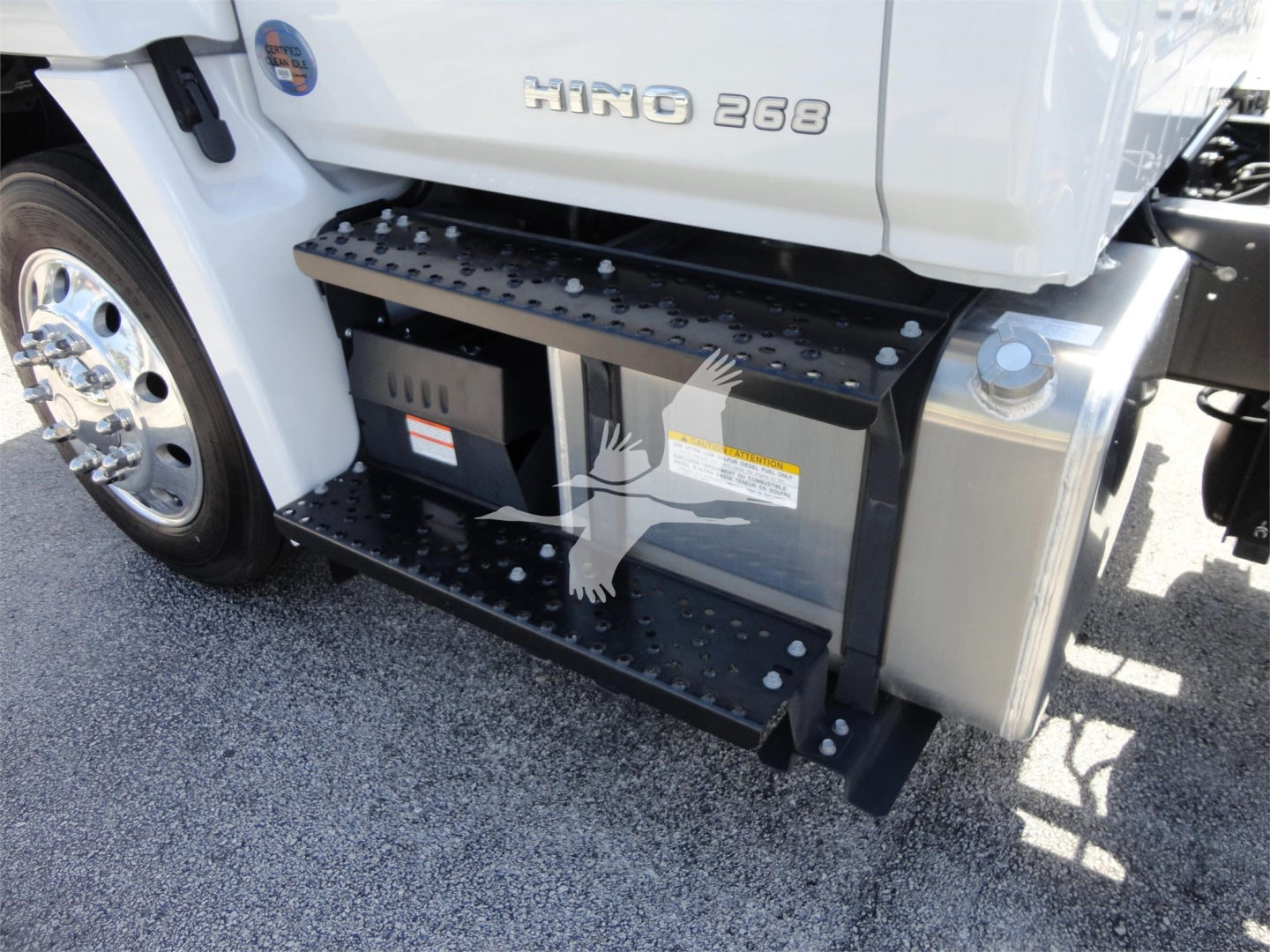 Hino 268a truck side with side step and fuel/equipment boxes visible under cab, chrome wheel and white body.