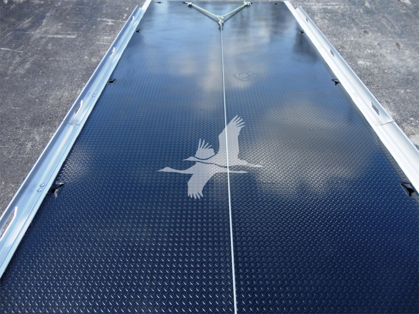 Truck bed with diamond plate surface and a central seam, a white bird decal visible on the bed.