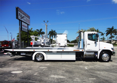 White Hino 268A rollback tow truck in side view with flatbed and hydraulic wheel lift, stock J51795.
