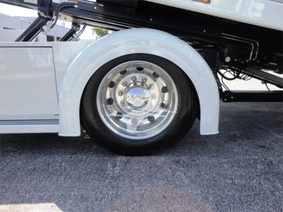 Truck wheel well and chrome wheel on a 2022 Hino 268A rollback truck showing white fender and partial undercarriage.