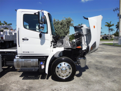 Truck cab of a white 2022 Hino 268A with hood open showing front wheel, chrome hub, and side step. Visible tag area and engine bay.