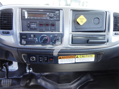 Dashboard interior of a 2022 Hino 268A rollback truck showing steering wheel area, radio, climate controls, switch panel, and warning label