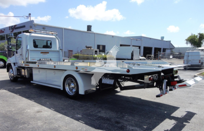 Hino 268A rollback tow truck side view showing flatbed with hydraulic winch and rear towing apparatus.