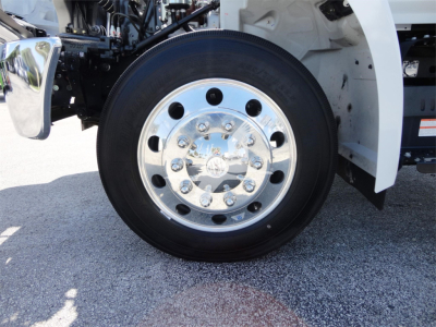 Truck wheel and chrome hubcap with black tire on white fender, front-left view of a 2022 Hino 268A rollback truck.