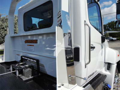 Truck rear cab area showing JERR-DAN decal and chrome vertical grab rail on a white Hino 268A rollback truck.