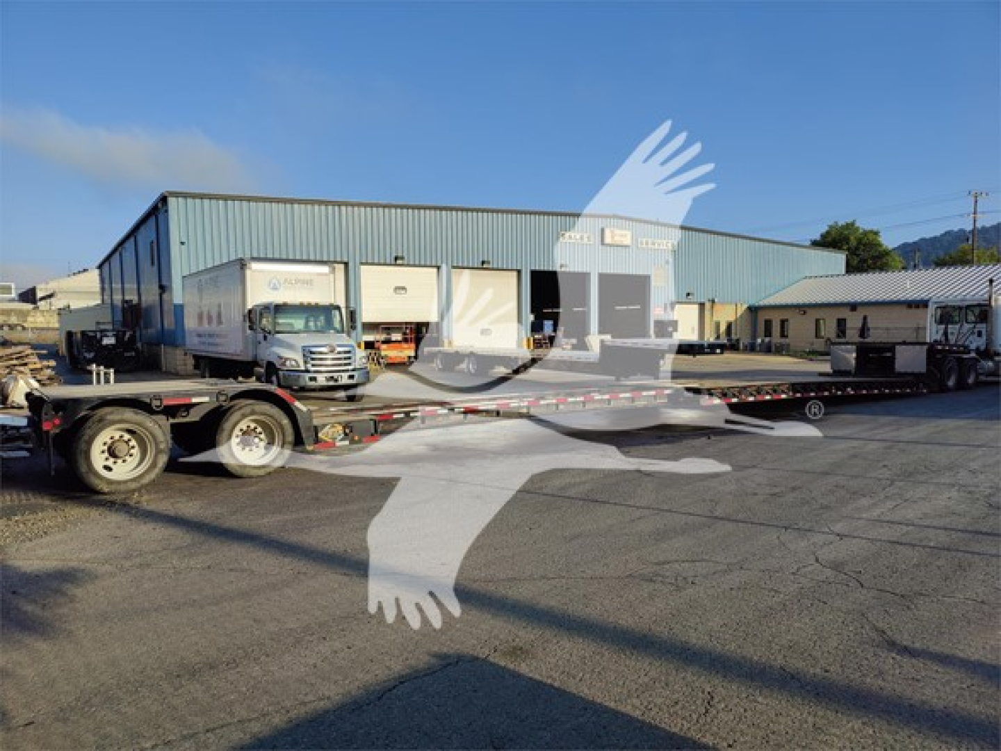 Trailer parked outside a blue warehouse with a Fontaine LXT-40 double drop expandable trailer on a flatbed truck, stock number 53-5975, VIN 57J653206L3577453.