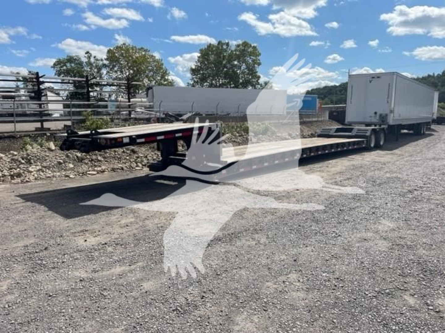 Trailer shown in a used Fontaine Renegade LXT-40 configuration, double drop expandable trailer with a gooseneck and two trailers connected, gravel lot, blue sky.
