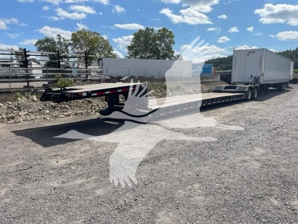 Trailer shown in a used Fontaine Renegade LXT-40 configuration, double drop expandable trailer with a gooseneck and two trailers connected, gravel lot, blue sky.