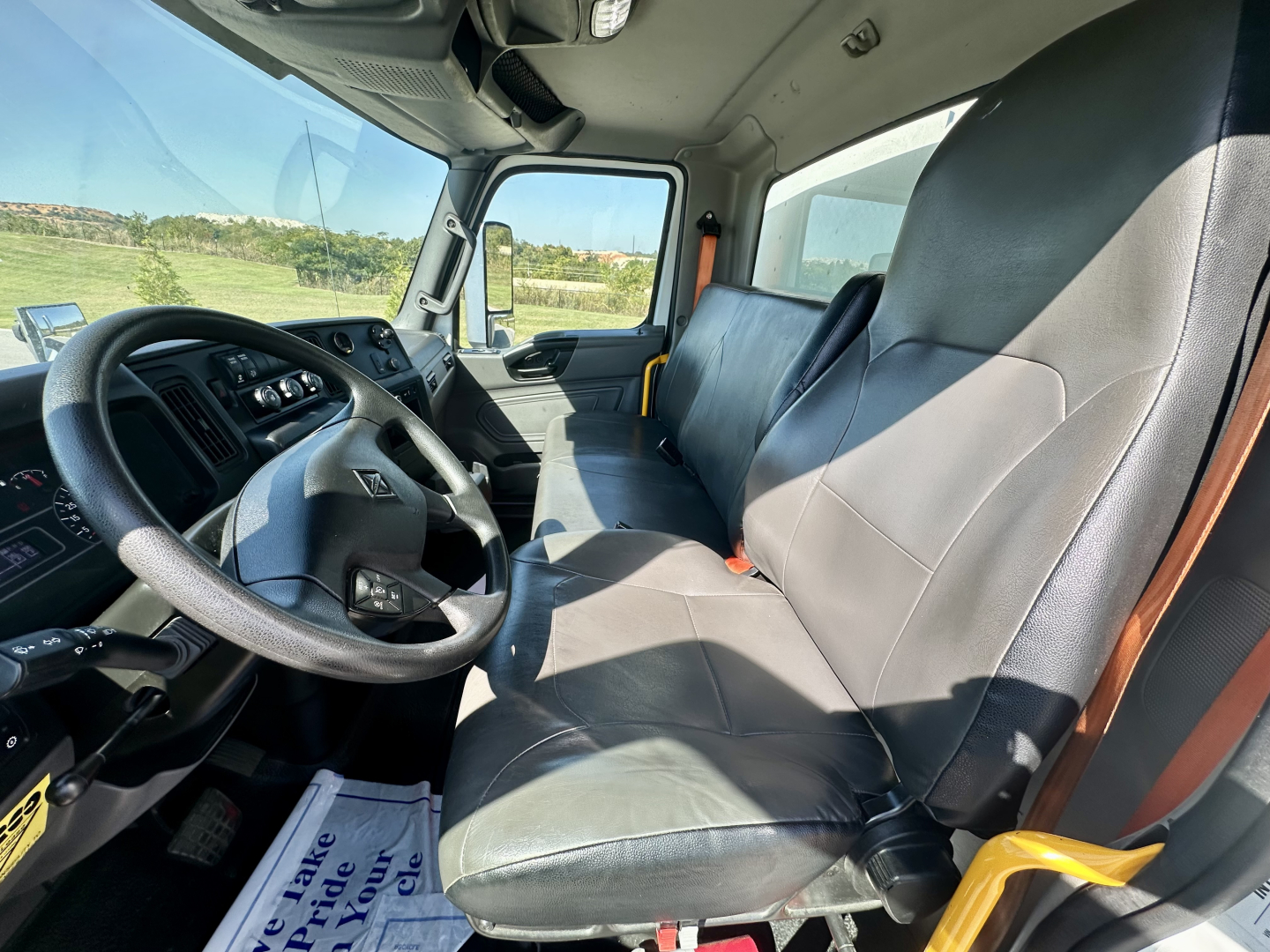 International MV607 cab interior showing steering wheel, driver seat, and bench passenger seat.