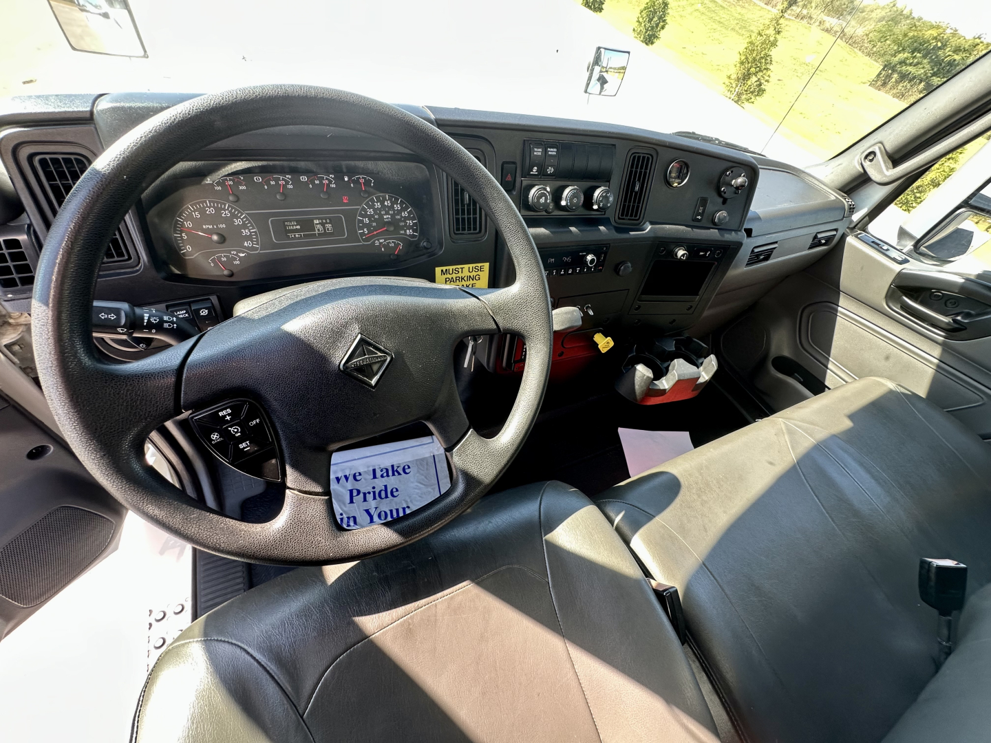 Truck interior showing steering wheel, dashboard gauges, and center console of a 2023 International MV607 with visible instrument cluster and controls.