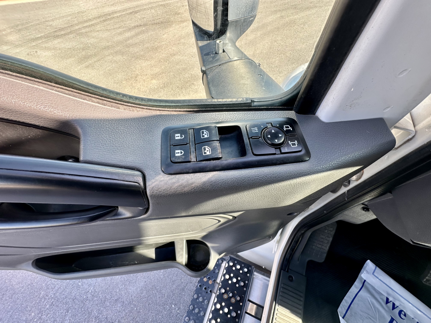 Truck interior door panel showing window control switches and mirror adjustment knob in driver-side door.