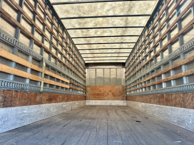 Empty cargo box of a 2023 International MV607 truck, interior view with wooden side rails and metal roof beams.
