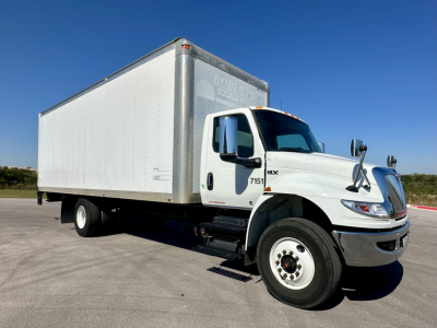 Box truck with long white cargo box and white cab, International MV Series, truck numbers 7151 on door, dual mirrors, large front grille.