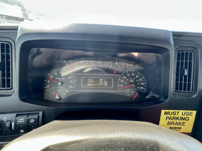Dashboard cluster of a used 2023 International MV607 showing speedometer and gauges; visible text includes MUST USE PARKING BRAKE sticker on the right.