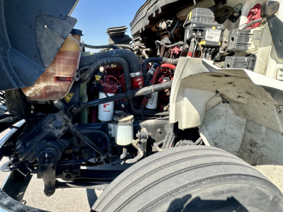 International MV607 engine bay showing coolant reservoir, filter, hoses, and wiring. Visible components include coolant bottle, oil filter, air intake hoses, and battery area.