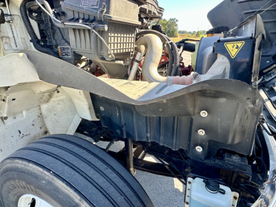 International MV607 engine bay showing front suspension and coolant reservoir with hoses and label.