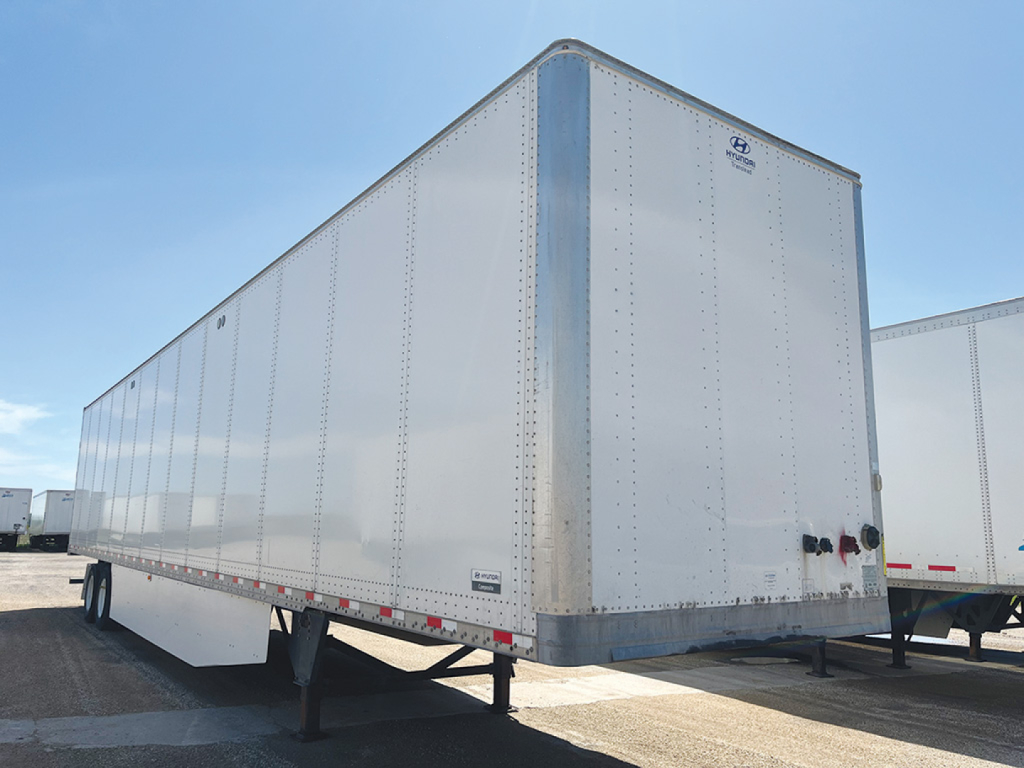 Trailer side and rear of a white Hyundai plate van trailer showing riveted aluminum panels and a rear bumper with taillight area.