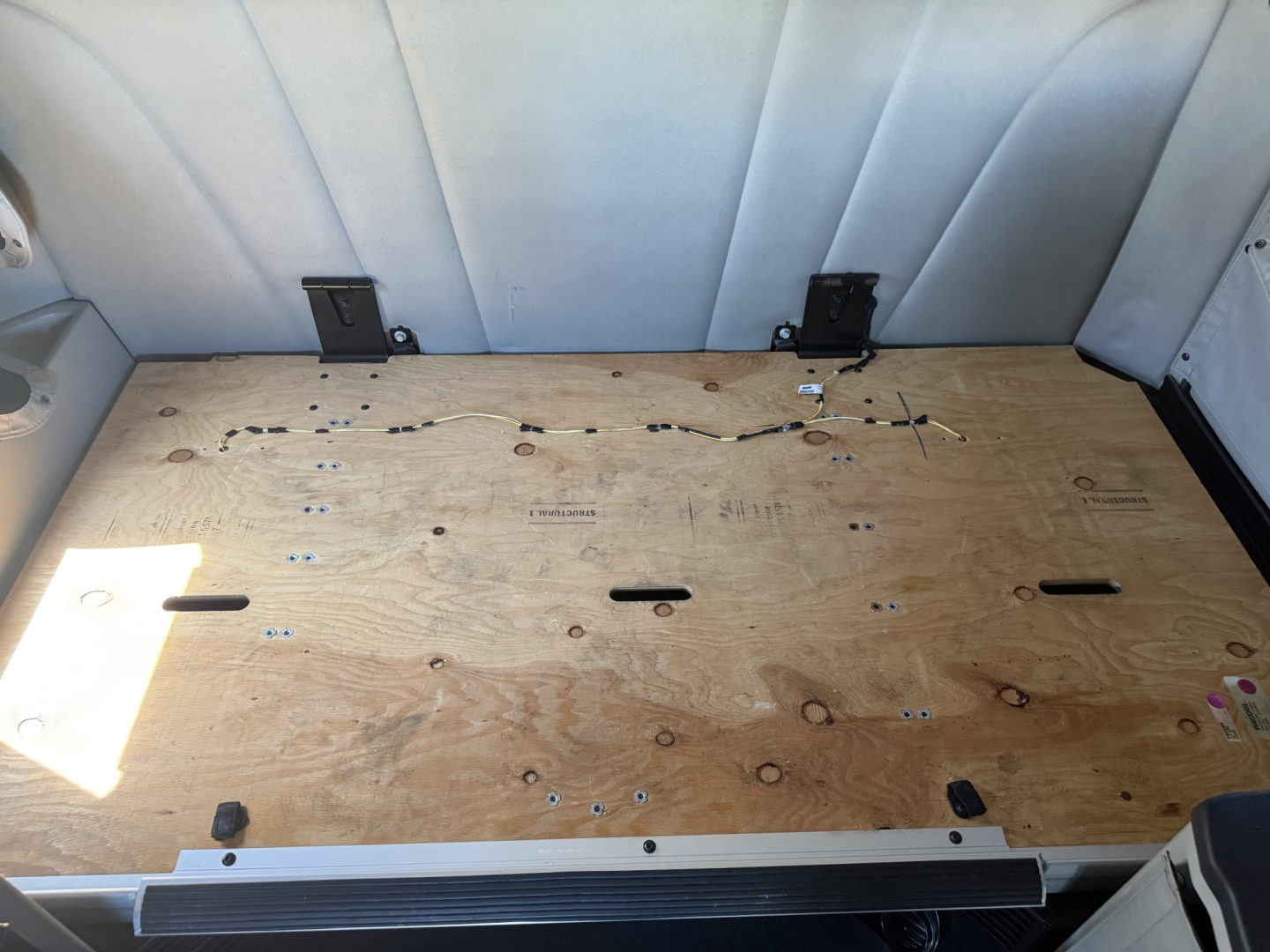 Rear cargo area of a Peterbilt 579 with wooden floor, tie-downs, and side wall padding visible.