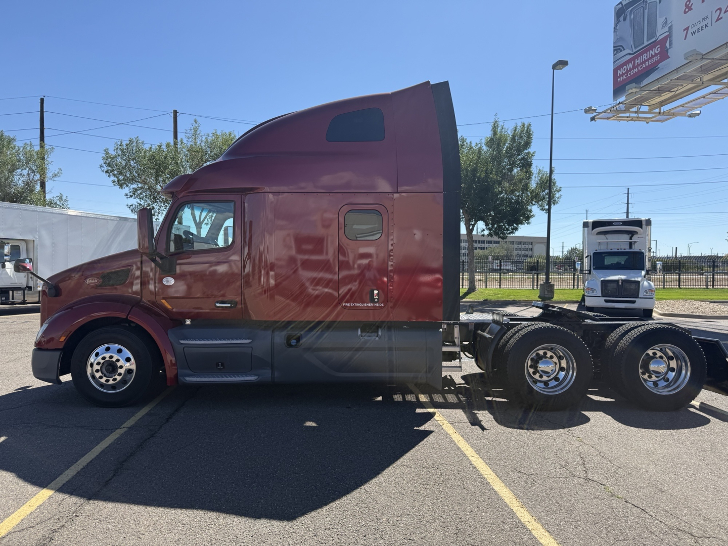 Peterbilt 579 conventional sleeper truck in maroon with dual rear axles, side view showing cab and chassis.