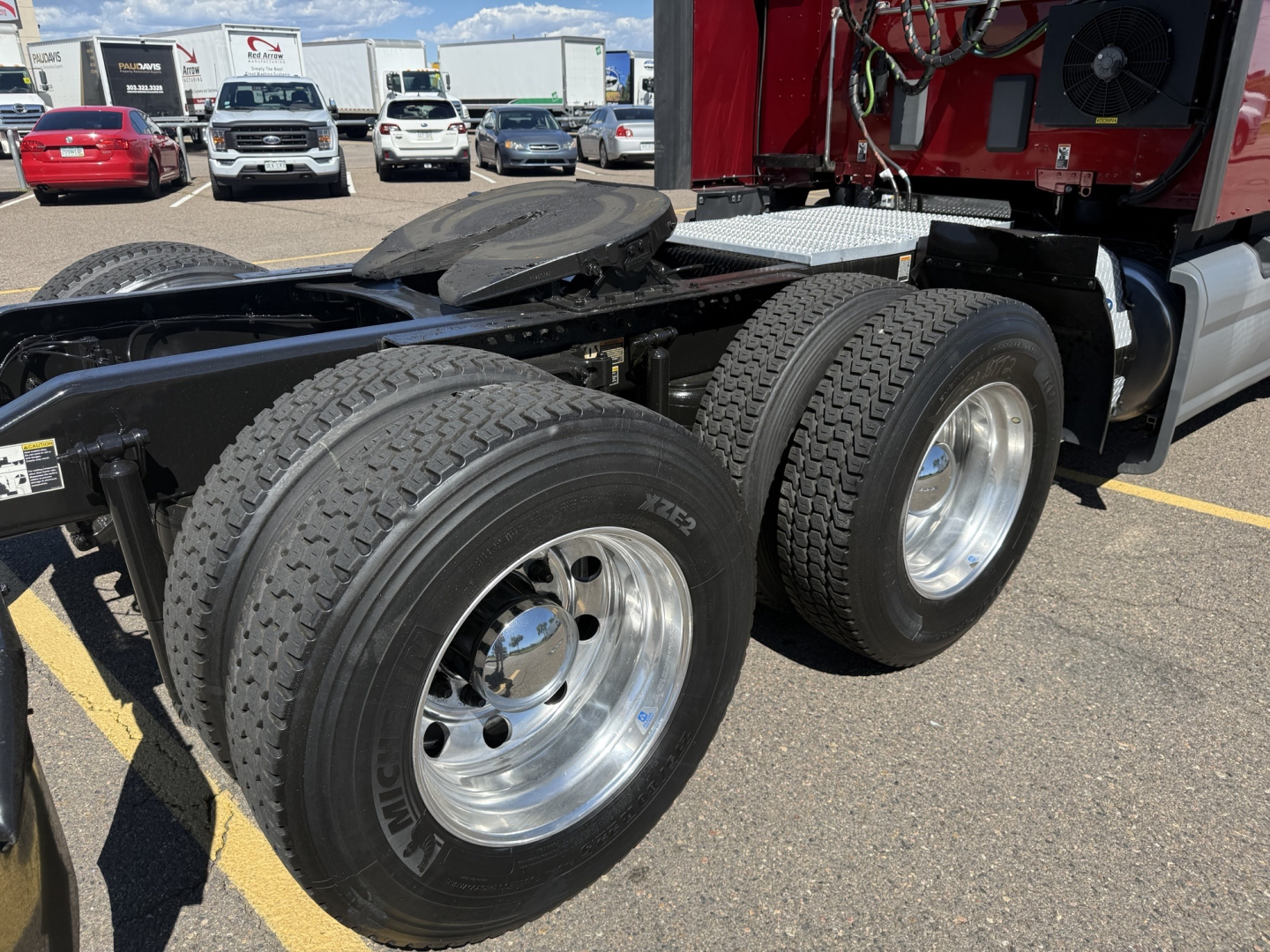 Peterbilt 579 chassis showing dual rear axles with large treaded tires and polished aluminum wheels; fuel tank, cab, and rear suspension visible.