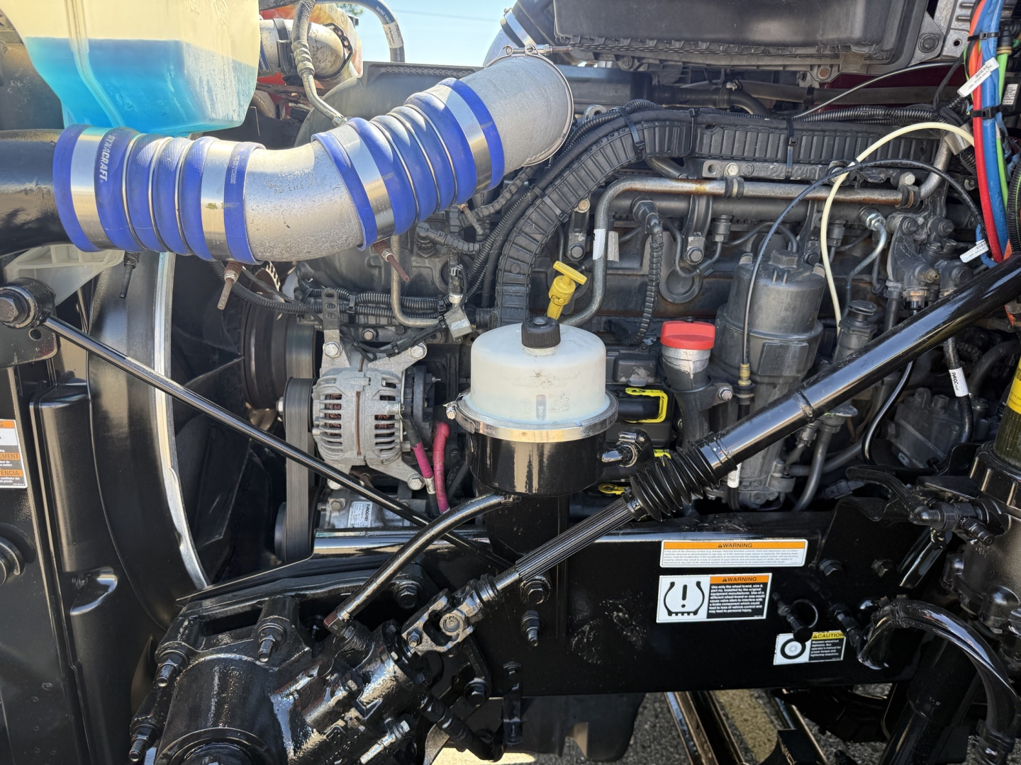 Peterbilt 579 engine bay with visible coolant reservoir, turbo intake hose, and various hoses and electronics.