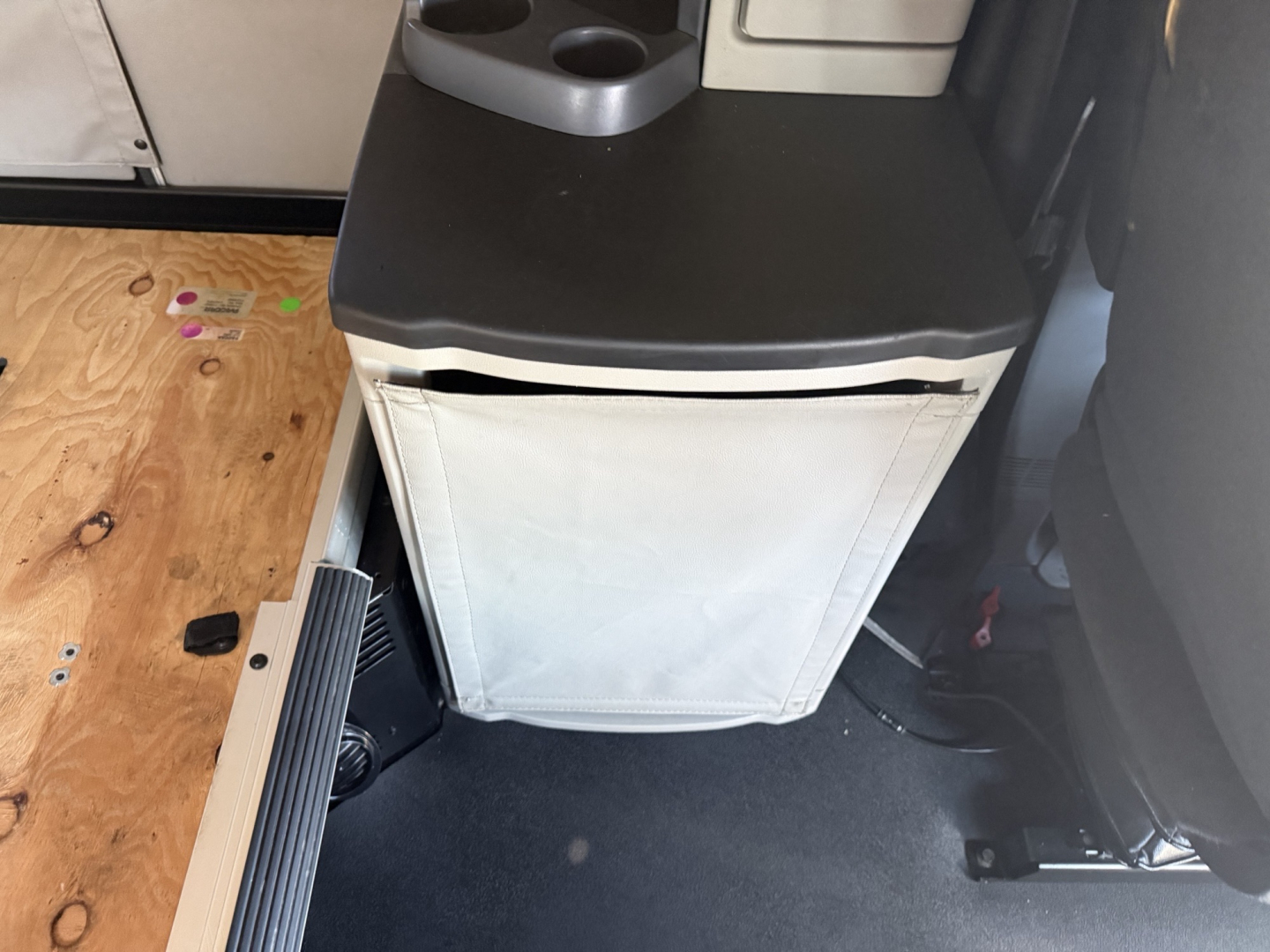 Peterbilt 579 cab interior showing a small cooler or cabinet with white fabric door and black top, cup holder area and surrounding truck interior components.