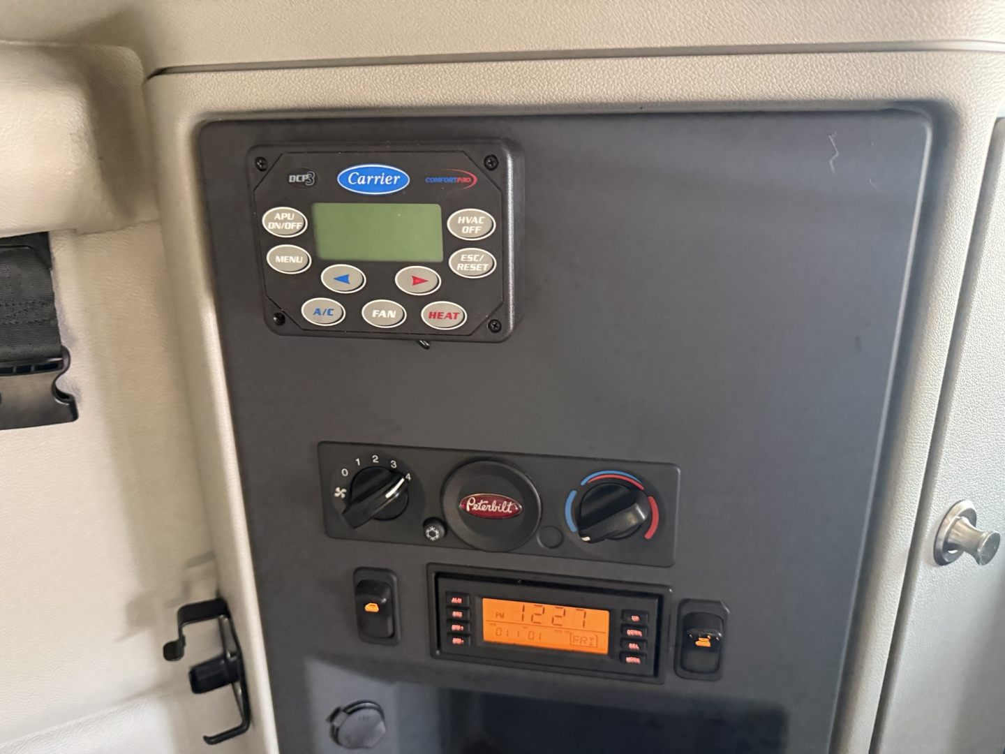 Panel with Carrier APU control and climate dials in Peterbilt 579 cab showing radio, gauges, and climate controls.