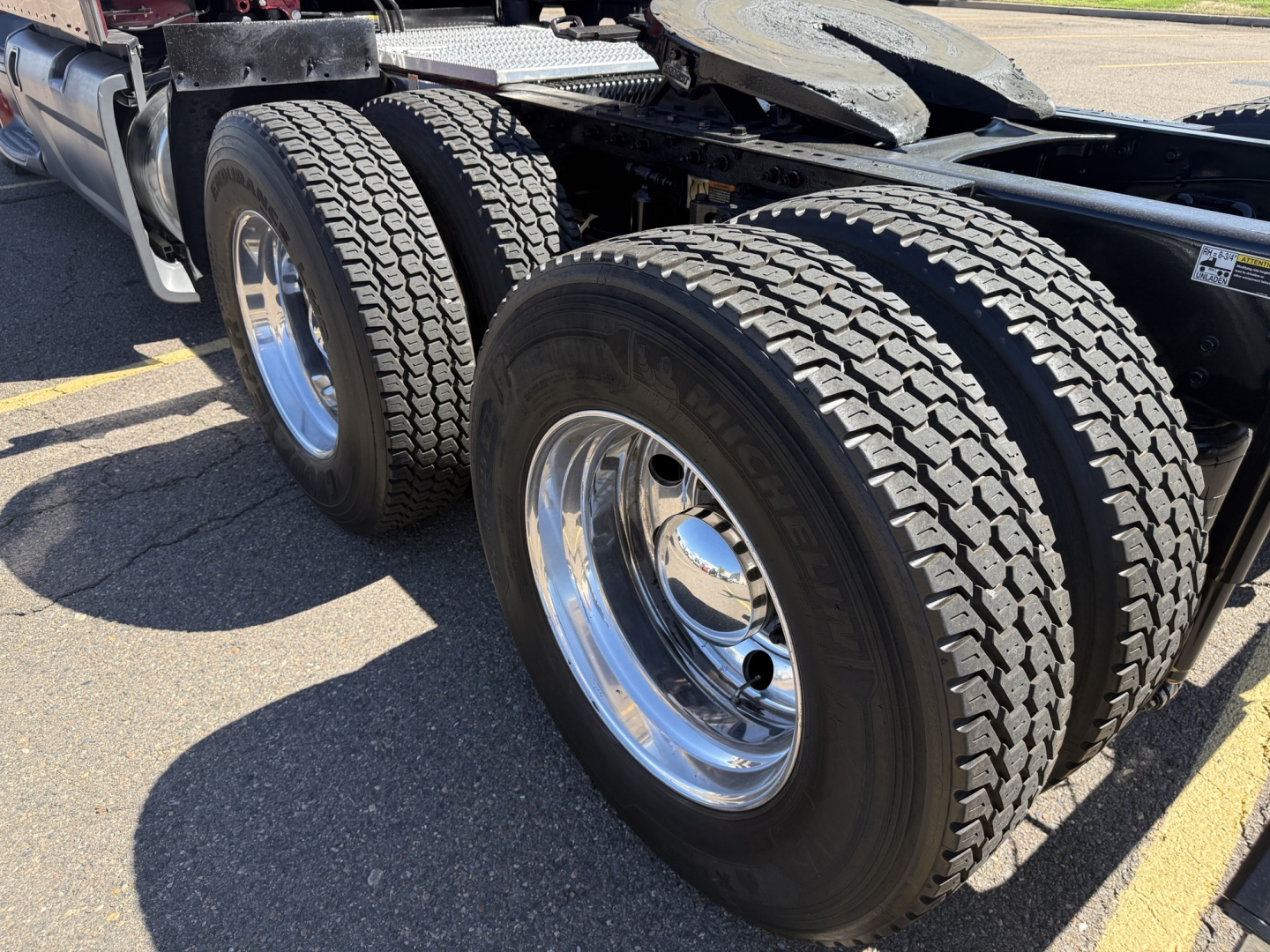 Peterbilt 579 chassis showing tandem rear axles and dual tires, chrome wheels, and part of the tractor’s frame.
