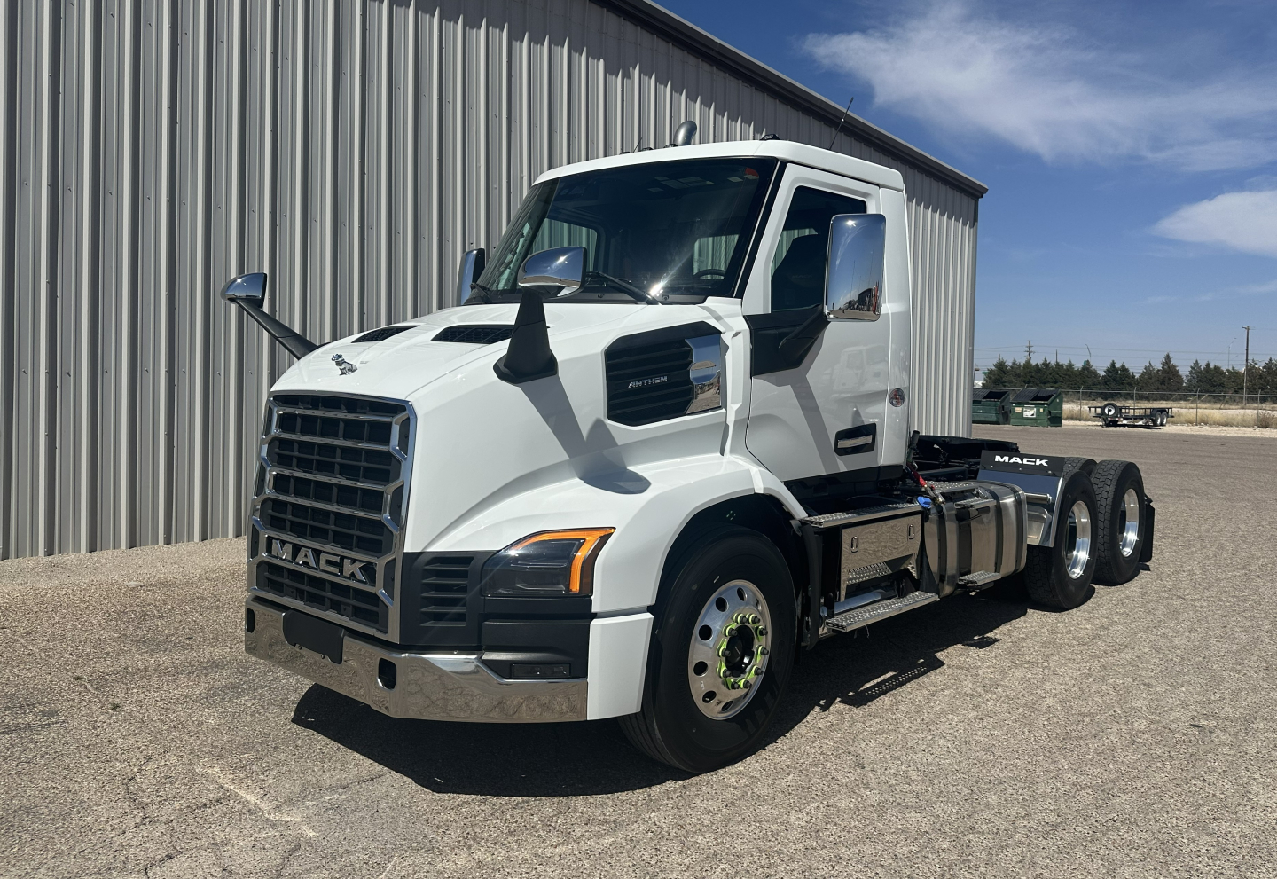 New white 2027 Mack AN64T conventional daycab truck parked outside a building showing front and side views with dual rear axles.