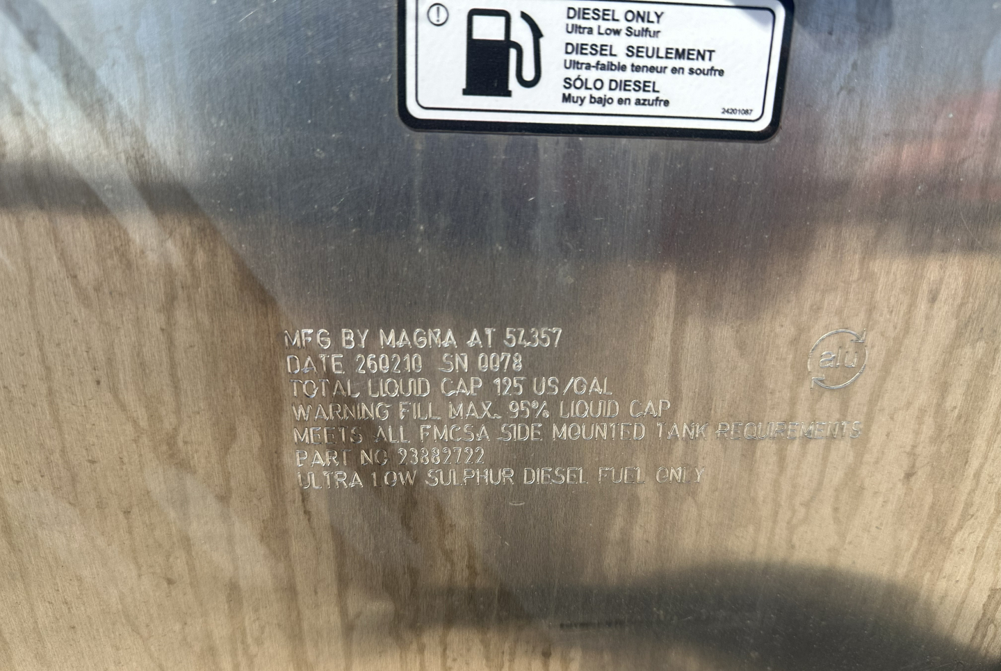 Label on diesel tank with warning and specifications: "AS S…?" text visible including FUEL CAP, TOTAL LIQUID CAP 125 US GAL, 0?  The text is partially obscured but includes warnings and capacity lines.