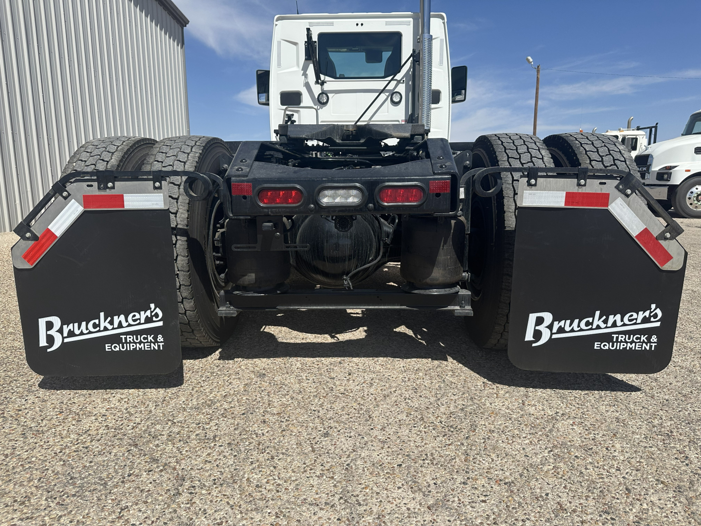 Rear view of a ?mack AN64T truck chassis showing dual rear axles and mud flaps with Brückner logos.