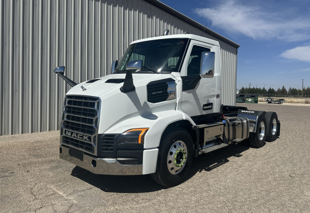 New white 2027 Mack AN64T conventional daycab truck parked outside a building showing front and side views with dual rear axles.