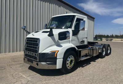 New white 2027 Mack AN64T conventional daycab truck parked outside a building showing front and side views with dual rear axles.
