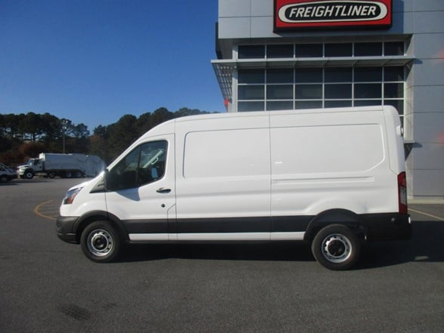 Ford Transit cargo van side view showing white body, single sliding panel, black bumper, Ford wheel wells.