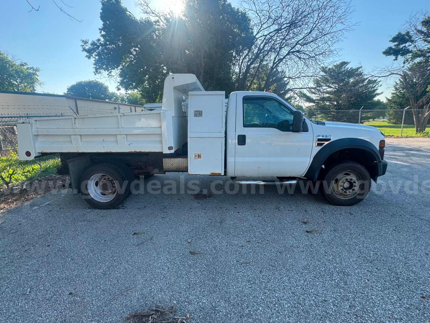 Ford F-550 dump truck side view showing dump bed and utility compartments.