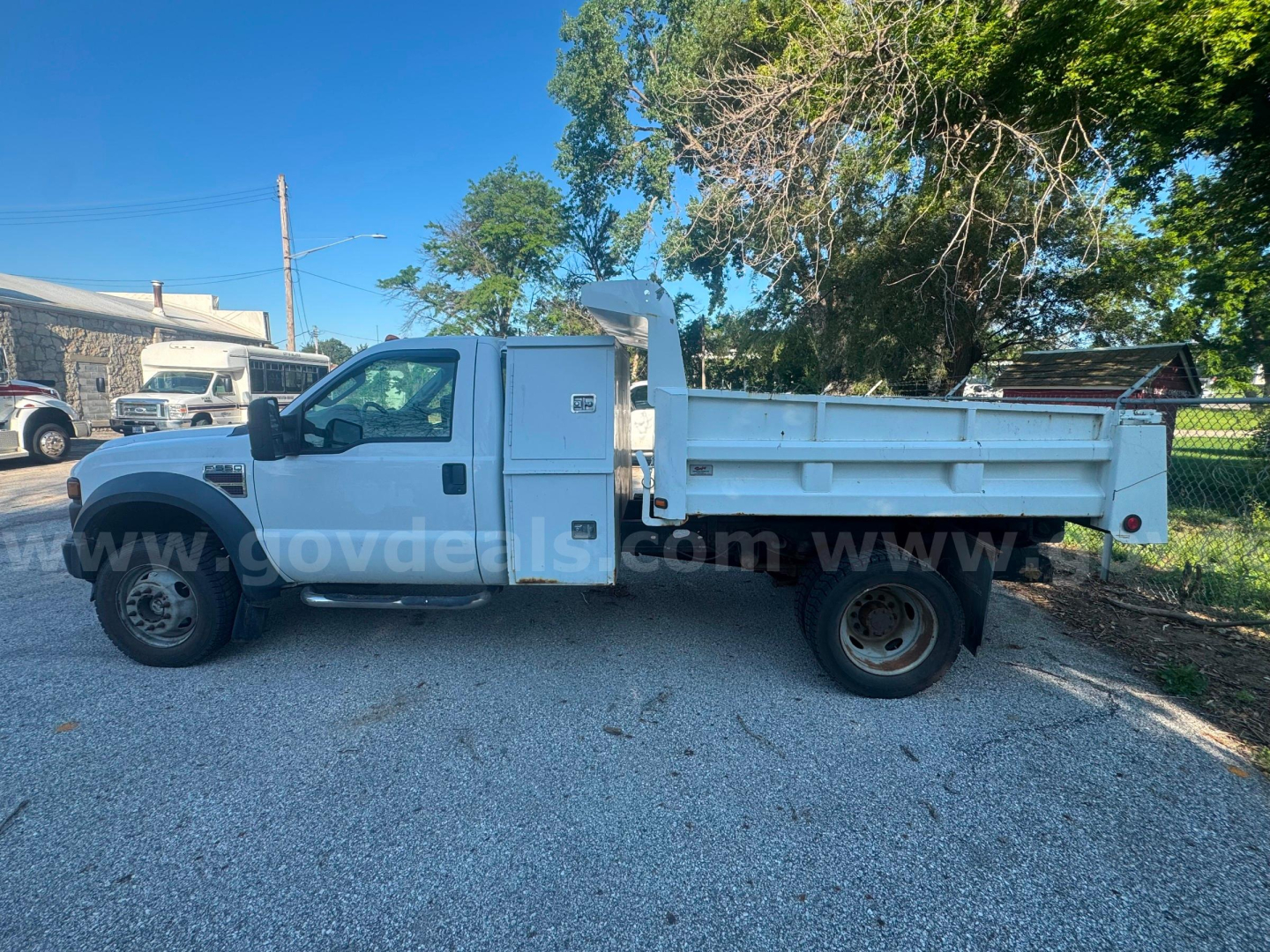 Side view of a white 2008 Ford F-550 dump truck with dual rear wheels and dump bed, VIN 1FDAF57R88EE54561, stock 6577-641, parked on gravel.