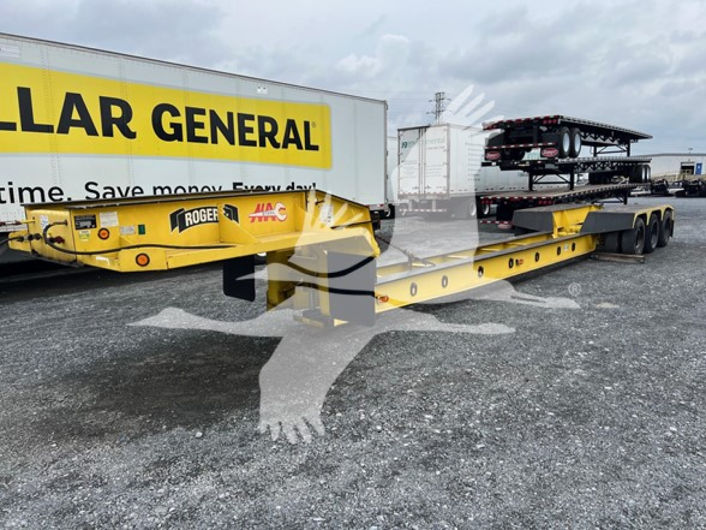 1988 Rogers 50 Ton beam trailer under a Caterpillar General yellow truck, with multiple stacked trailers in background