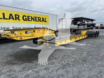 1988 Rogers 50 Ton beam trailer under a Caterpillar General yellow truck, with multiple stacked trailers in background
