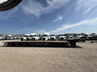 Landoll 455B-53 55 Ton traveling axle lowboy trailer with multiple white trucks in background.