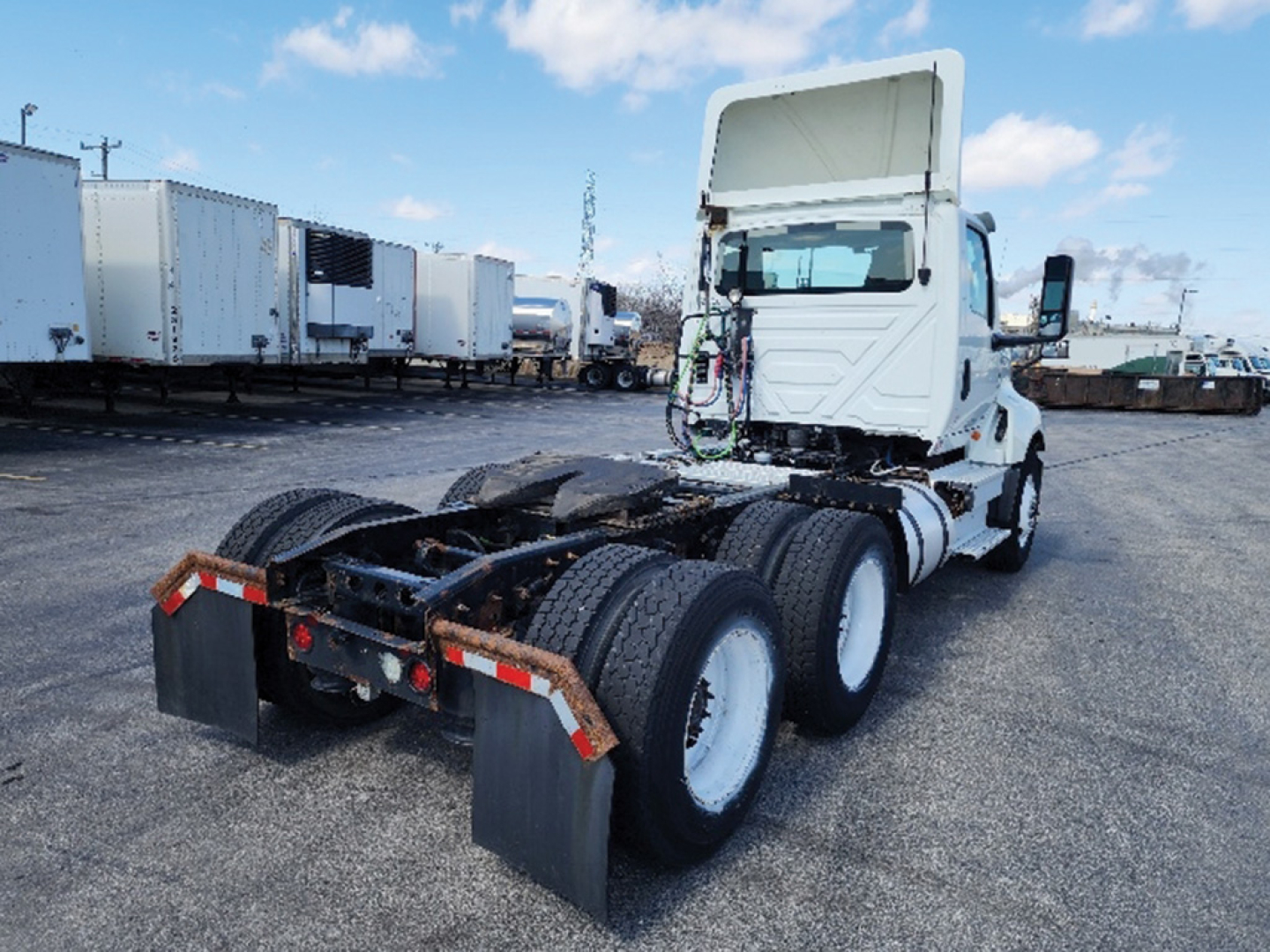 Truck chassis rear view showing seventh wheel, dual rear axles, and cab of a 2019 International LT625 tractor in a used truck lot.