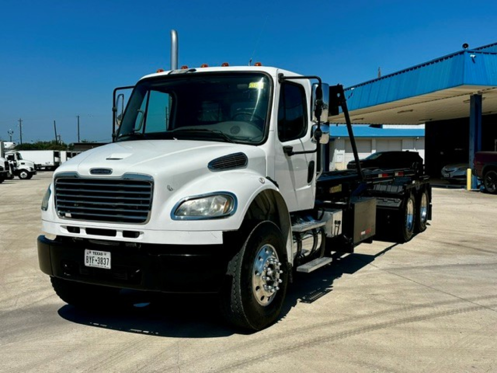 Rollback tow truck 2013 Freightliner M2 106 with white cab and black chassis showing side view and equipment bed.