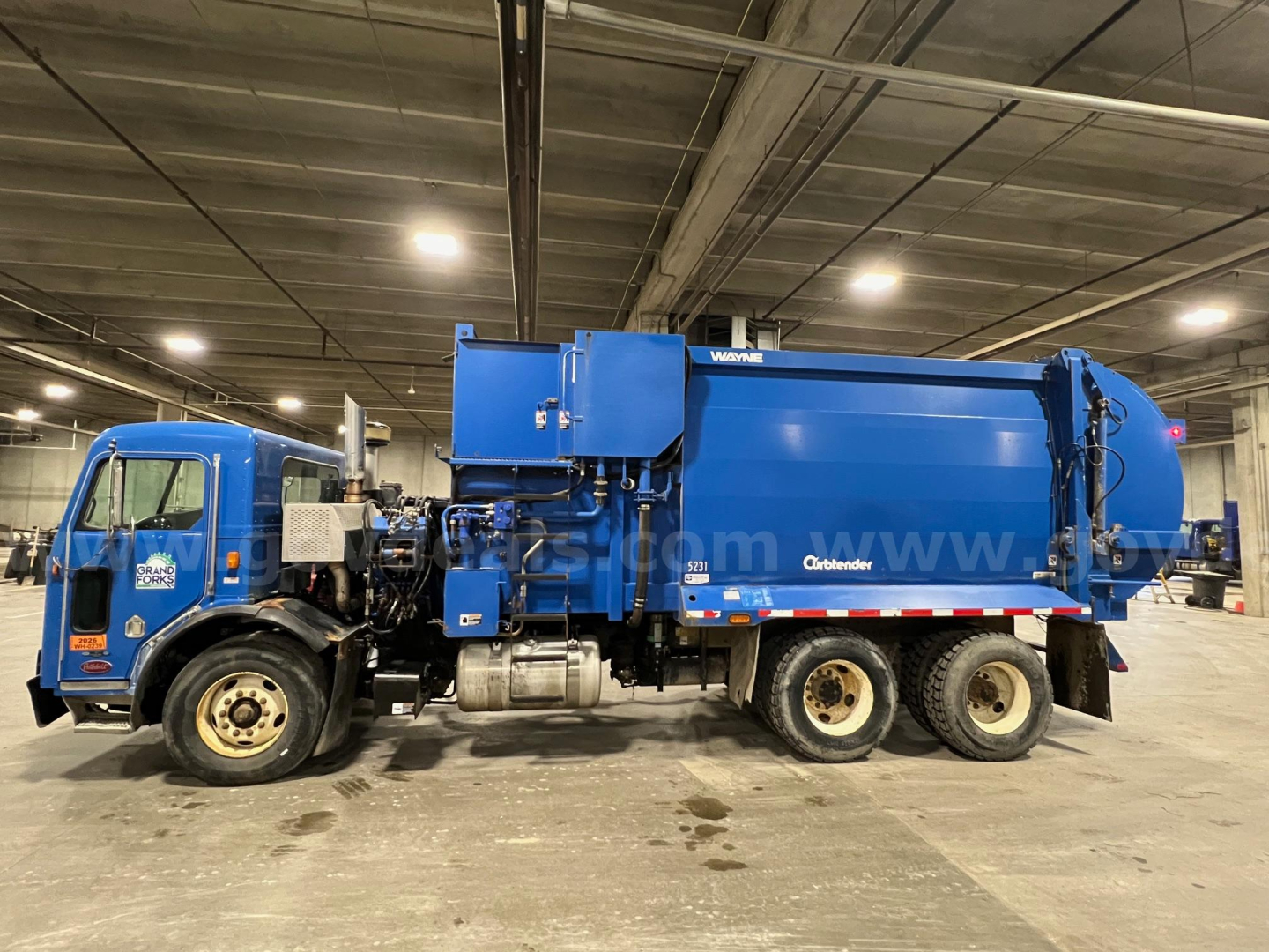 Peterbilt 320 garbage truck side view showing blue vacuum/compactor body and cab, stock number 4677-226, VIN 3BPZL00X5BF115774.