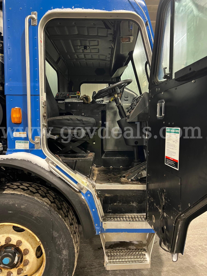 Peterbilt 320 cab interior and driver door area showing steps, steering wheel, and dashboard.