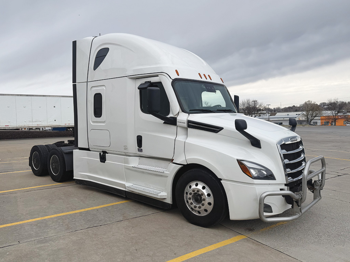 Truck cab side view showing 2023 Freightliner Cascadia126 with sleeper, front bumper guard, and dual rear axles.