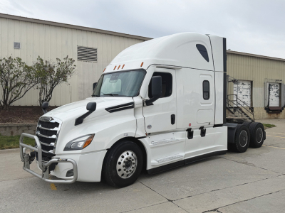 2023 Freightliner Cascadia126 tractor-trailer in showroom white with bull bar and side mirrors, front view.
