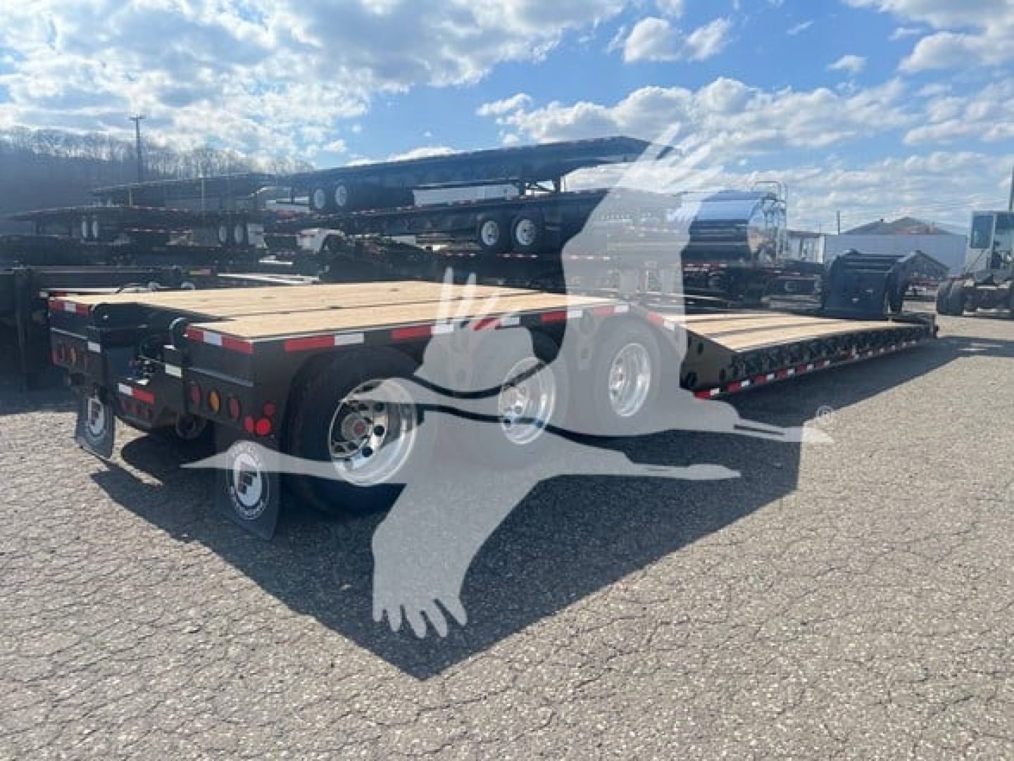 Trailer showing lowboy deck with dual axles and multiple wheels, flatbed with wooden deck, rear ramps, and reflective markers.