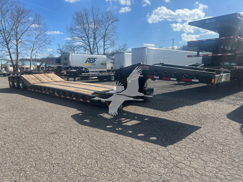 Fontaine paver trailer in an outdoor lot showing a lowboy with a decorative eagle graphic on the gooseneck and loaded deck.