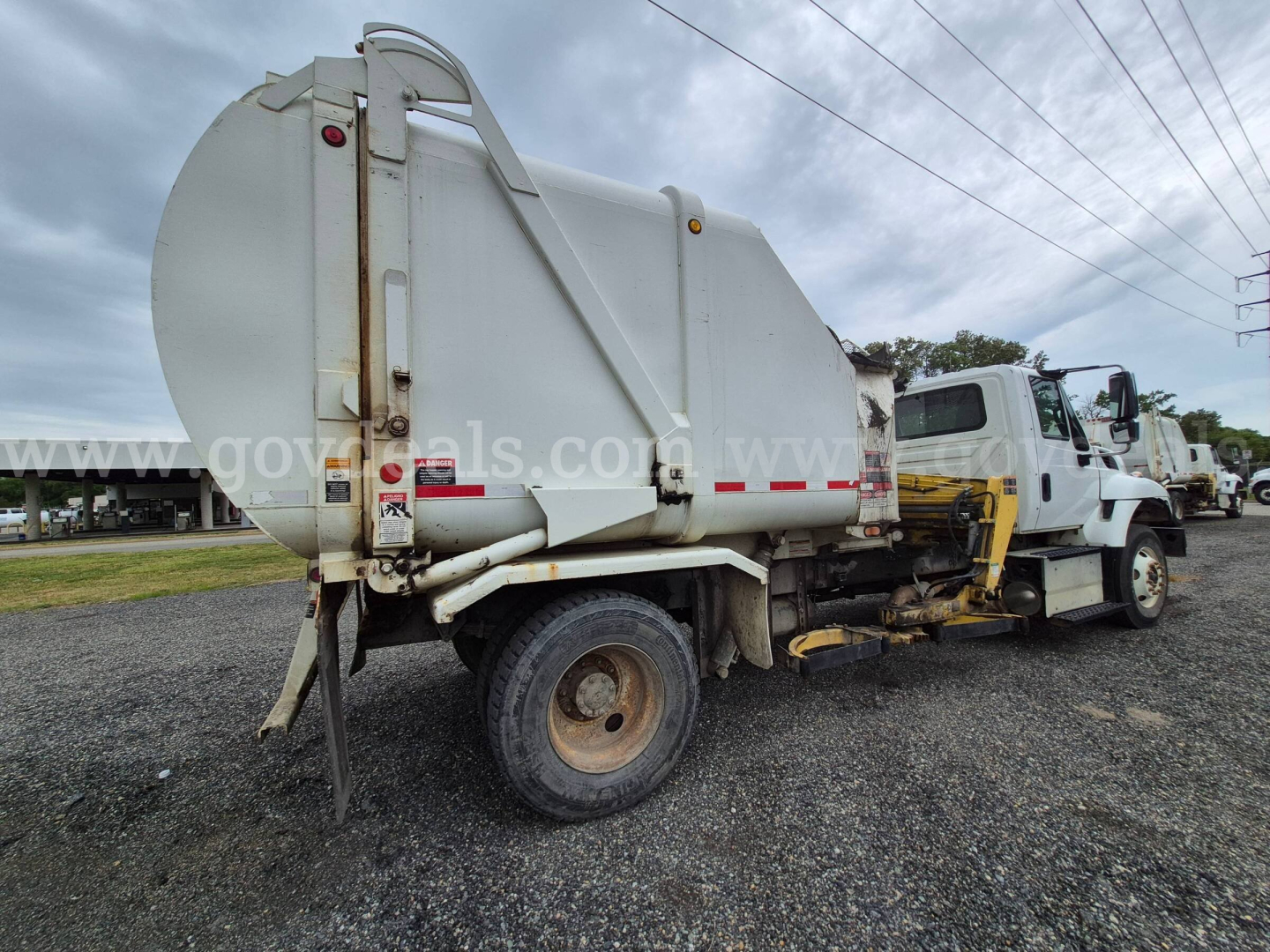Dump truck body showing rear view with large cylindrical tank and garbage collection configuration.