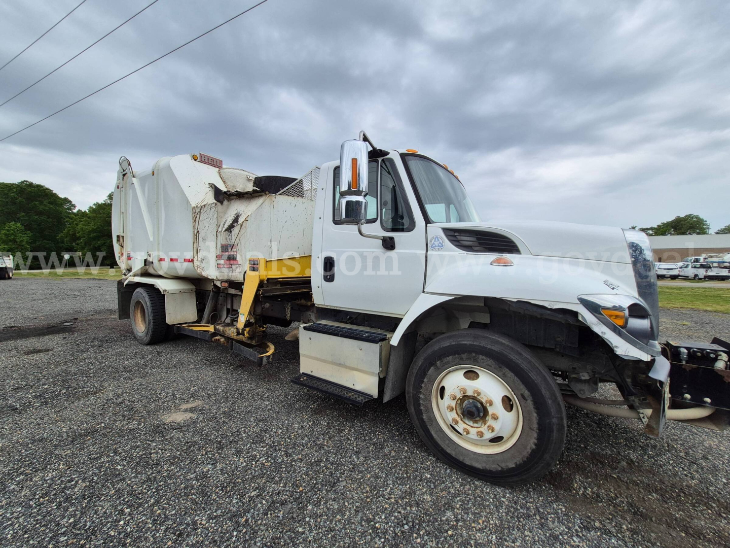 International 7400 garbage truck in-service showing front grille and side view with attached refuse body and hydraulic components.